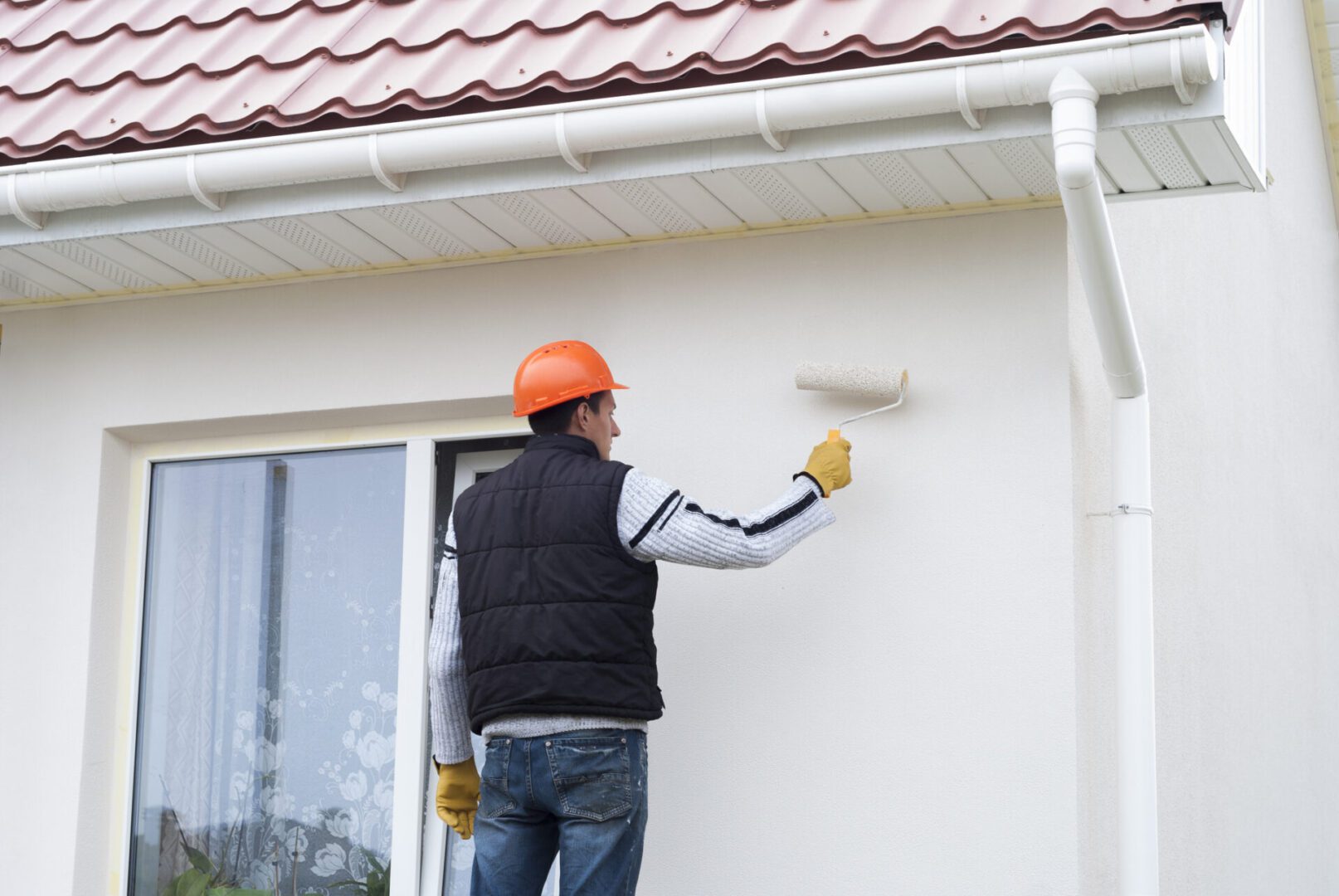 construction worker is painting a wall with a roller